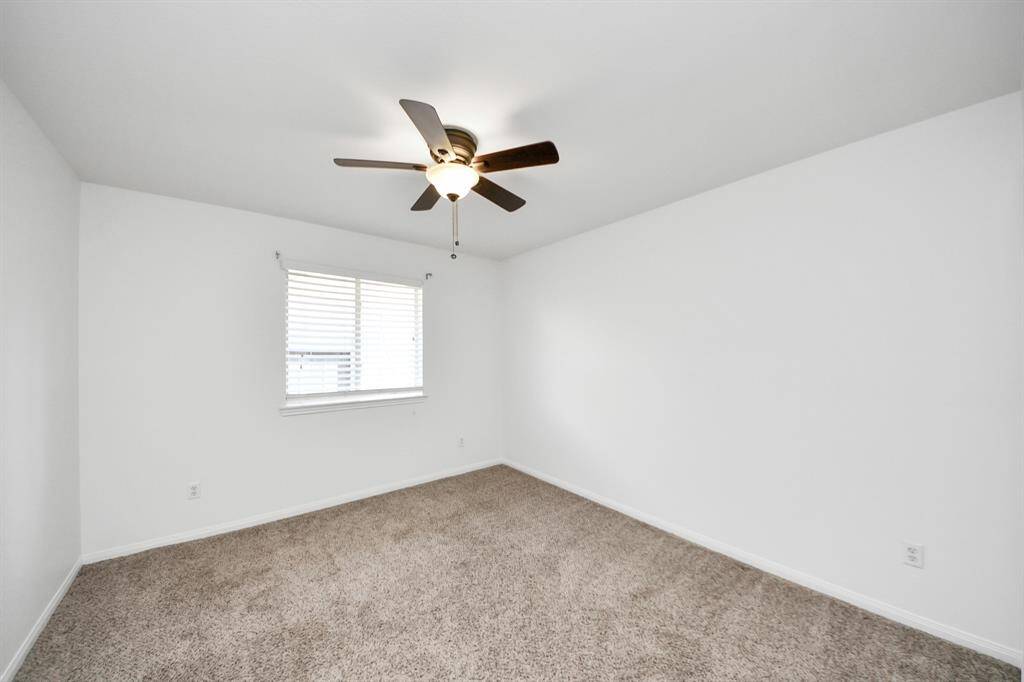 Large carpeted bedroom with ceiling fan and ample space for your furniture layout.