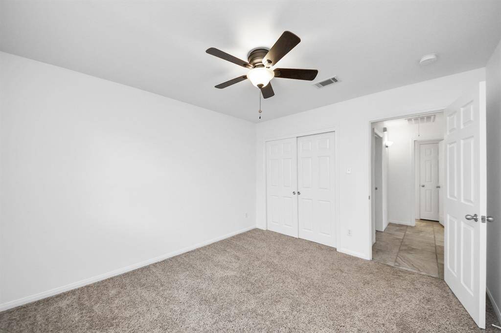 Comfortable secondary bedroom with neutral tones, double-door closet, and ceiling fan.