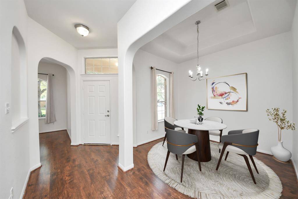Elegant formal dining space with tray ceiling, chandelier, and abundant natural light. (virtually staged)