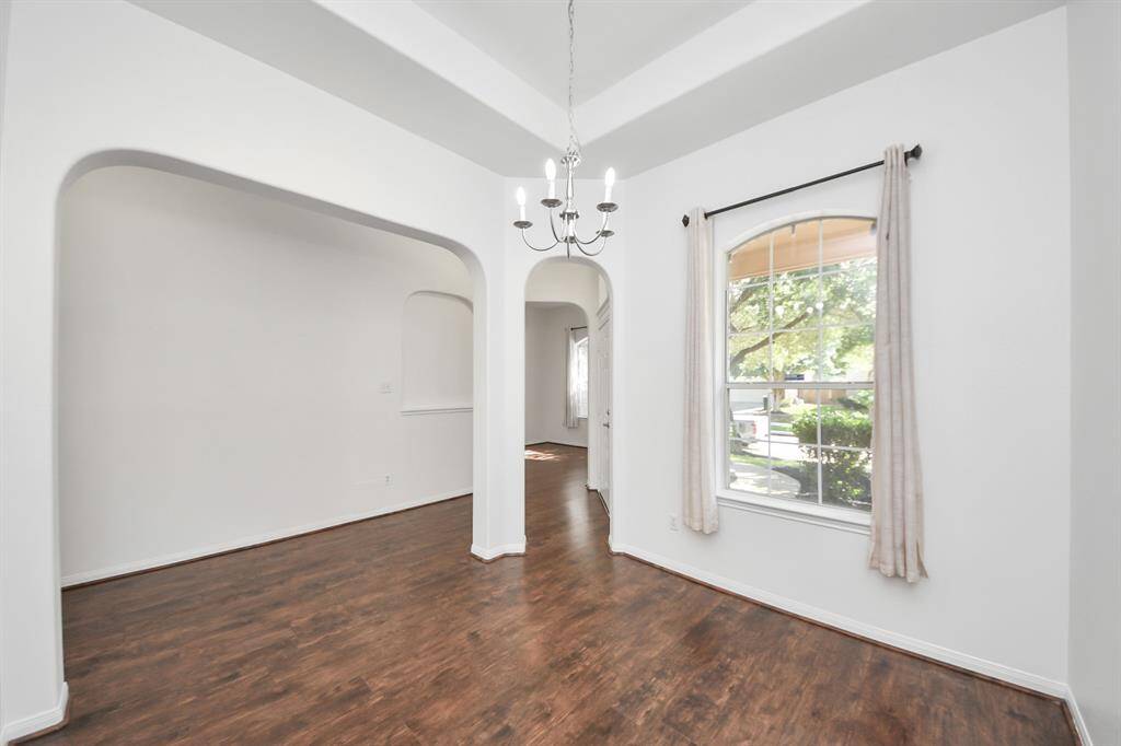 Spacious dining room with arched openings and large front-facing window for bright, airy views.