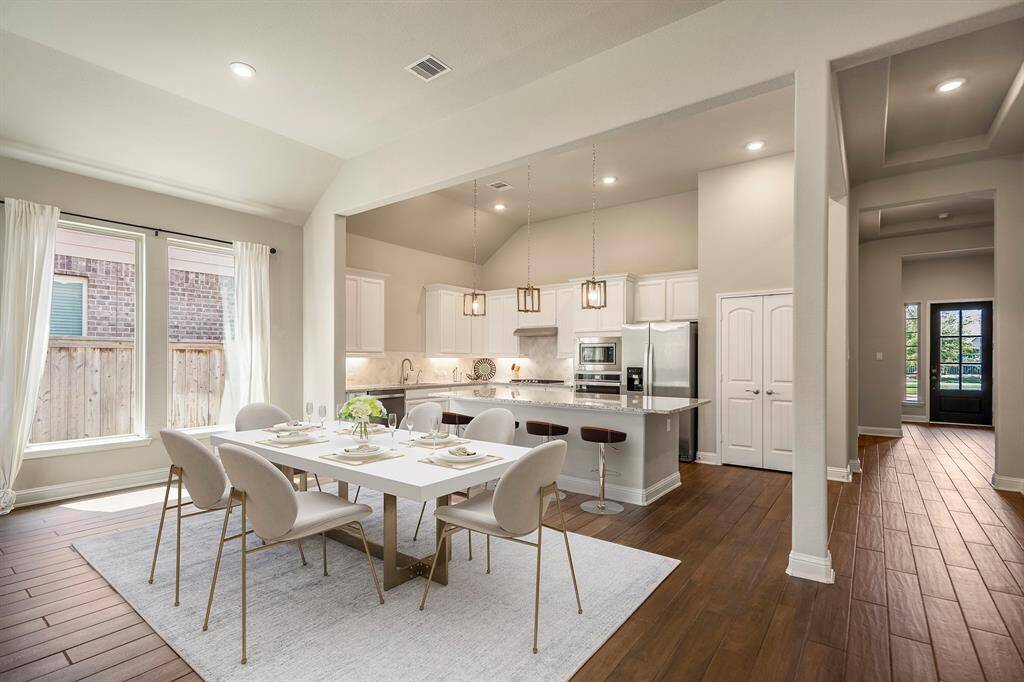 Down the long hallway from the foyer into the home, you have an open concept floor plan with an incredible island kitchen. (virtually staged dining table)