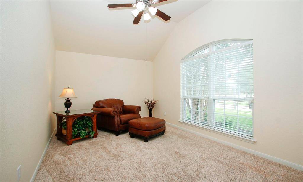 Study with newer carpet, neutral paint, arched windows, and fan with light kit.