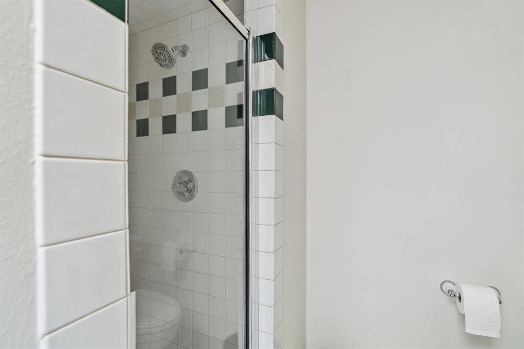 Tiled walk-in shower with glass door.