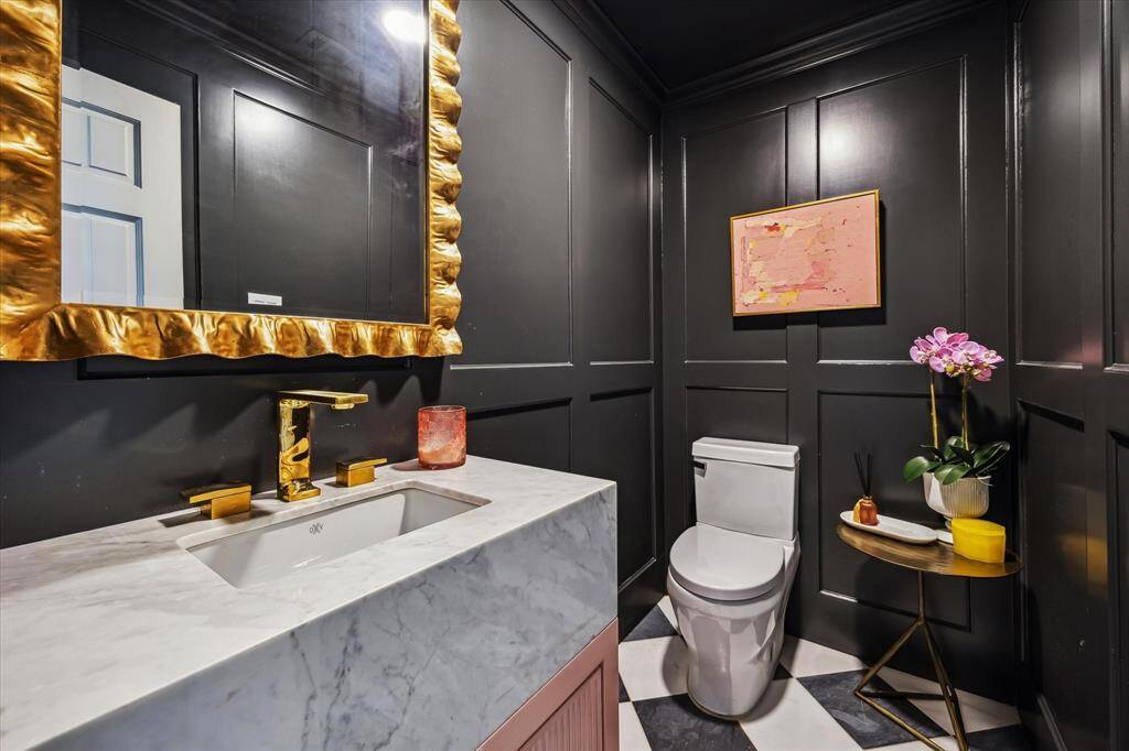 The powder bathroom features wood-paneled walls with marble tile flooring.