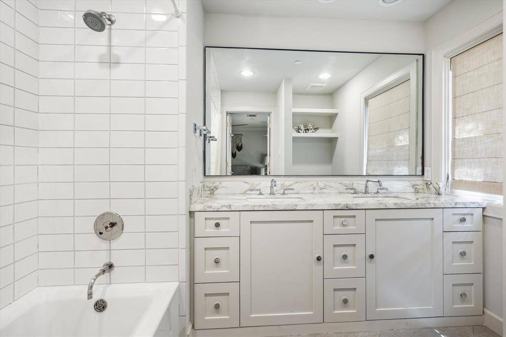 This secondary bathroom features dual vanities and a shower-bathtub combination.