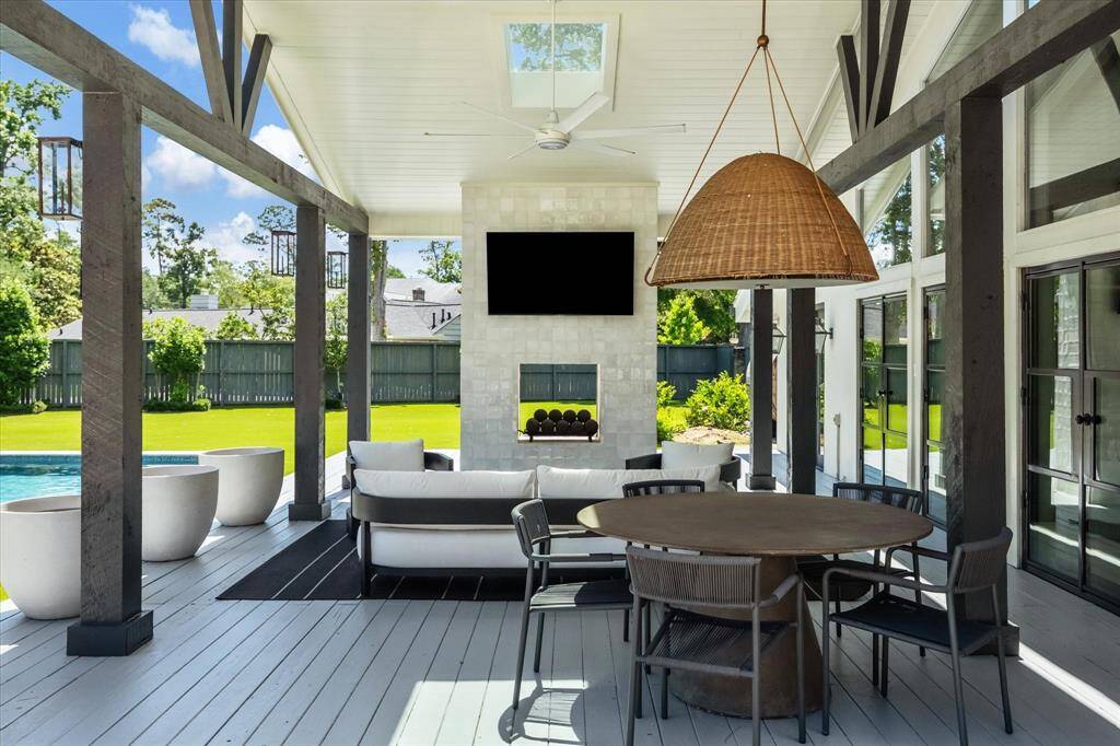The outdoor living area features a covered patio with fireplace and ceiling fan and overlooks the fully turfed backyard.