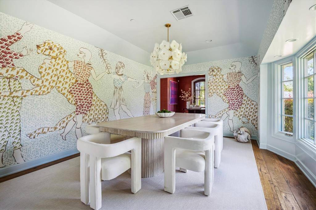 The formal dining room features a coved ceiling, wood flooring, and tall windows with views of the lush front yard.