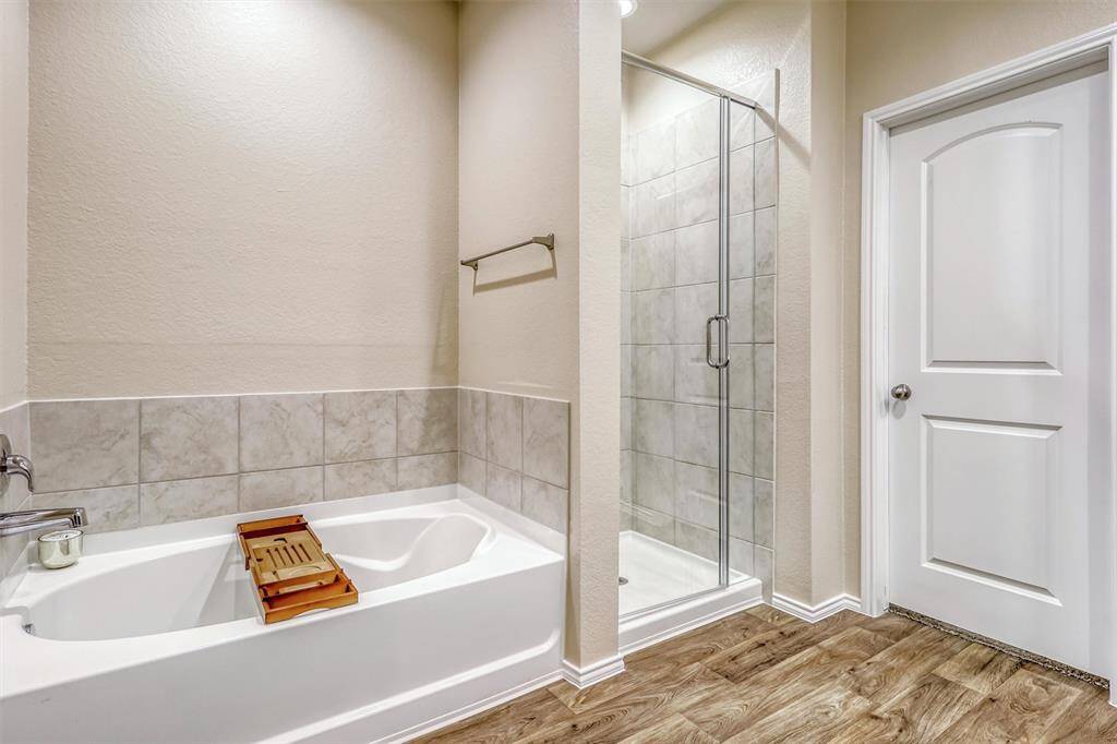 Unwind in the deep soaking tub or start your morning refreshed in the enclosed glass shower. Dual sinks and a dedicated vanity area make daily routines effortless and elegant in this primary en suite bath.
