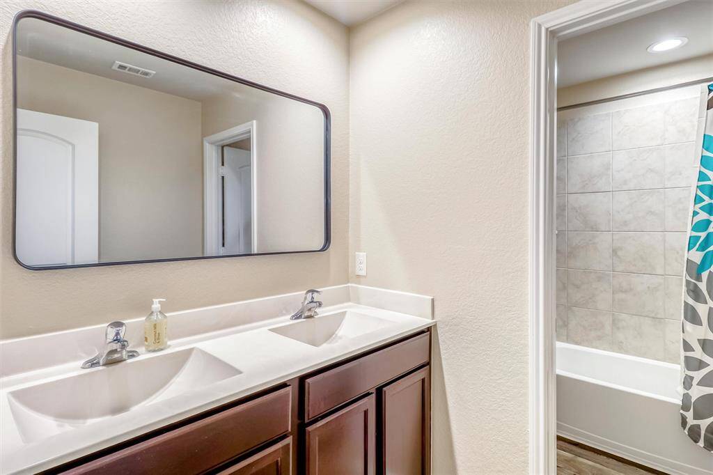 This full secondary  bathroom features a dual-sink vanity and a separate wet area, offering privacy and convenience for morning rush hours or evening routines.