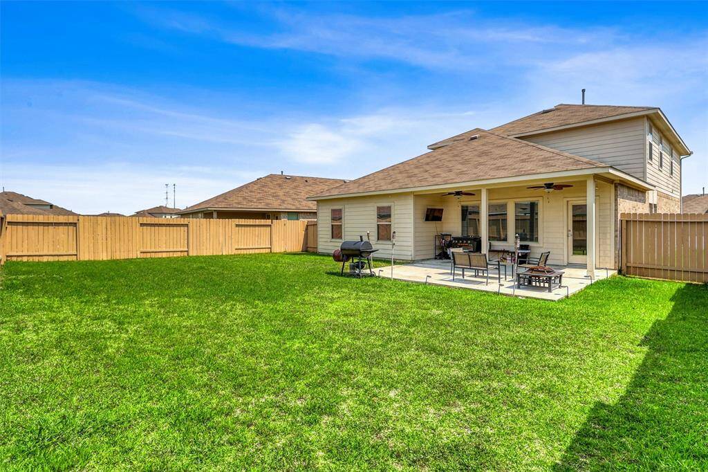 This outdoor living space blends comfort and versatility with both covered and open-air sections, a ceiling fan for warm afternoons, and room to host guests.