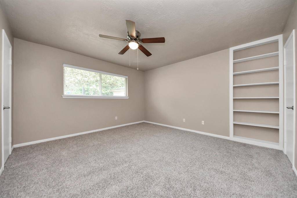 Spacious primary bedroom featuring a charming built-in bookshelf, perfect for displaying your favorite books or decorative pieces.