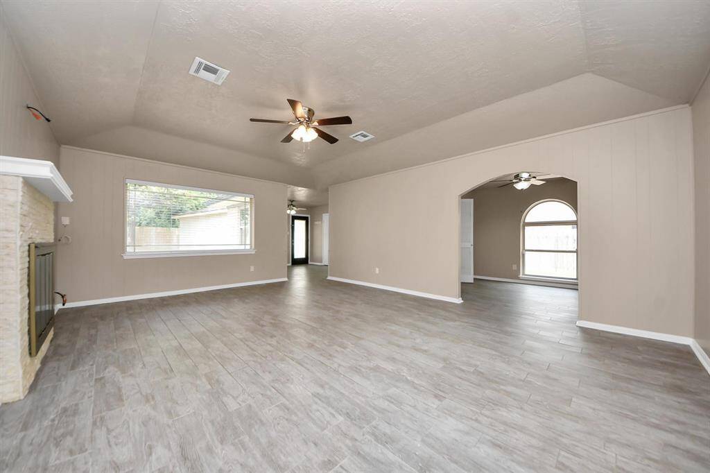 Step into a spacious living room featuring soaring ceilings and a cozy wood-burning fireplace—an ideal setting for both relaxed evenings and effortless entertaining.