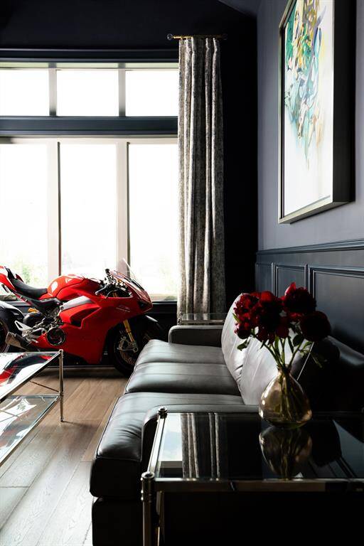 The home office features double glass doors that invite natural light into the space. It incorporates a cozy computer nook and custom cabinetry, accented by rich wood paneling and expansive windows that provide a view of the outside.