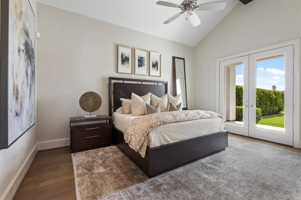 The downstairs guest suite features soaring vaulted ceilings and double doors that open directly to the backyard oasis, blending indoor comfort with outdoor tranquility.