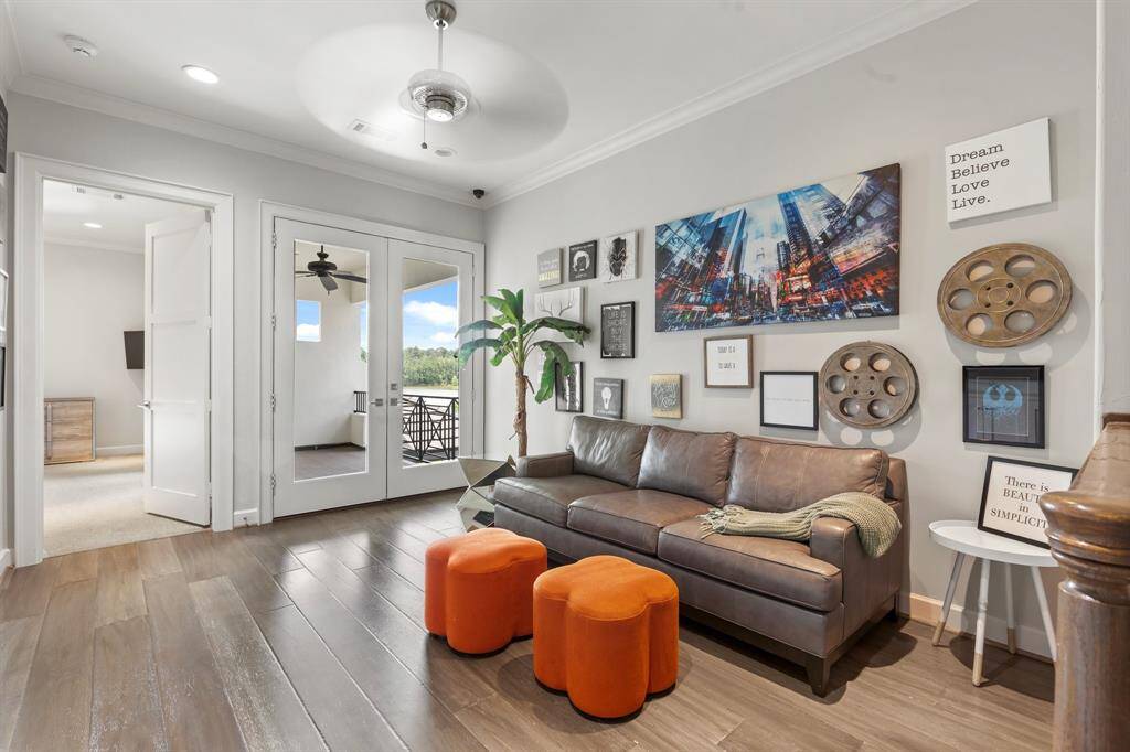 The inviting upstairs game and lounge area features custom cabinetry and elegant double doors that open to a breathtaking balcony overlooking the shimmering lake.