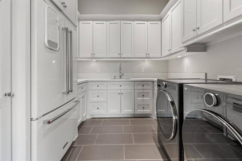 The downstairs laundry room, accessible through a stylish pocket door, is thoughtfully designed with a sink, a full refrigerator, and ample storage, making laundry day a breeze.