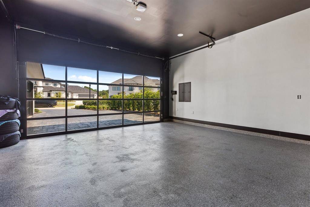 One of the two commodious garages, providing a total of 4-car storage, boasts an epoxy floor and sleek tinted glass front doors that add both functionality and aesthetic appeal.