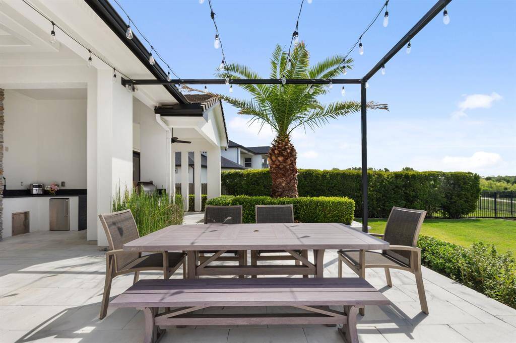 The charming outdoor dining area, adorned with twinkling hanging lights, creates an inviting atmosphere for al fresco meals while offering breathtaking views of the serene lake.