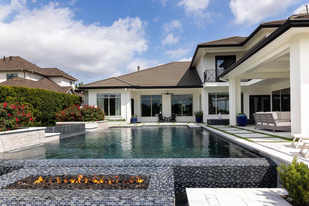 The large, tile-encased fire pit at the rear of the property provides a captivating focal point, where one can enjoy cozy evenings under the stars in an enchanting outdoor setting.