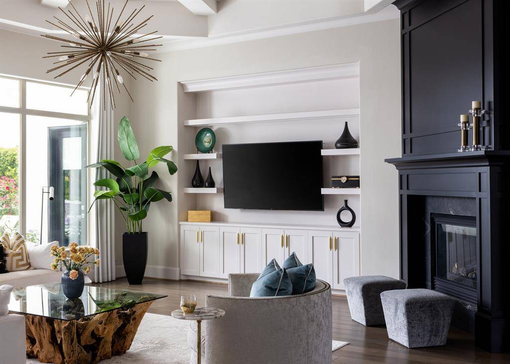 The expansive grand living room boasts floor-to-ceiling windows that flood the space with natural light and provide breathtaking views of the inviting pool and picturesque lake.