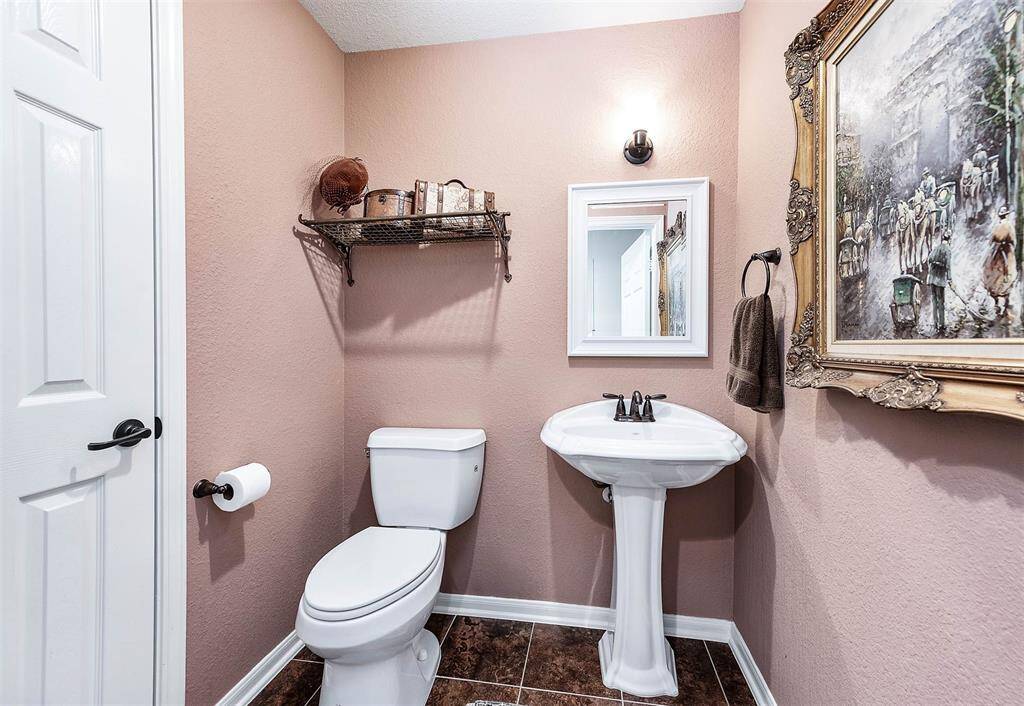 Half bath adjacent to office with pedistal sink, elevated toilet and large linen closet.
