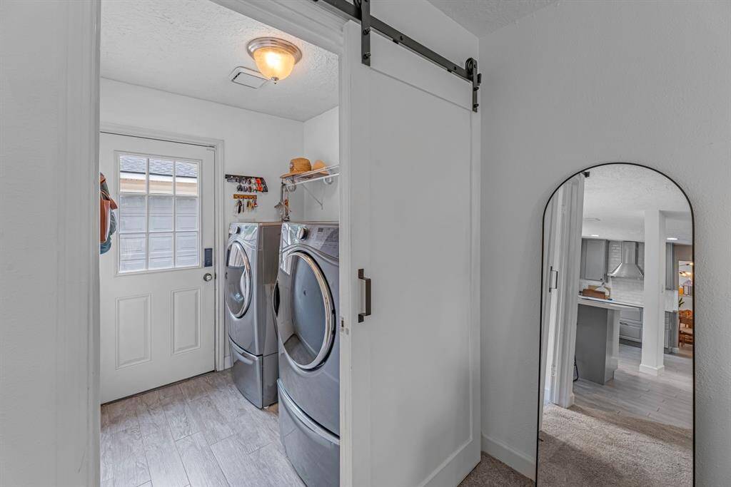 Laundry room is inside with a barn door and a door that leads outside.