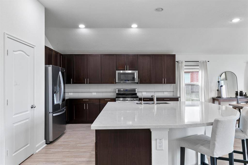 Look at the shine on those quartz countertops! Offering the perfect contrast to the dark, rich cabinetry, the kitchen has everything needed including stainless steel appliances.