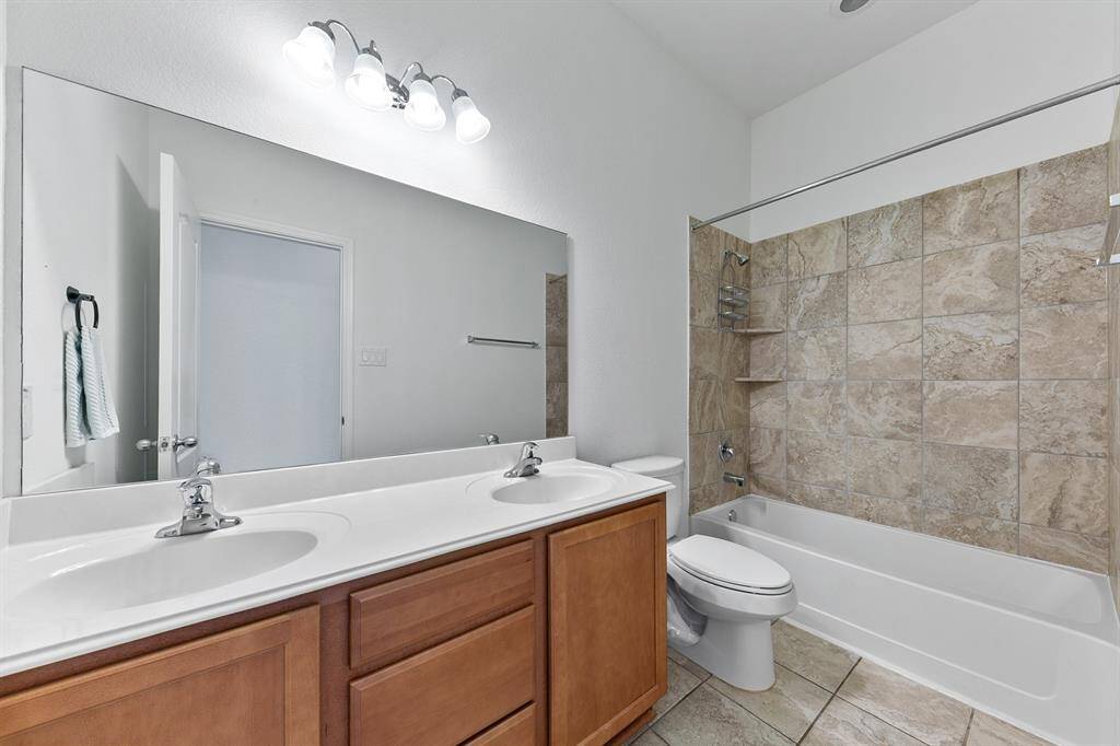 A traditional hall bath has a dual sink vanity under an oversized mirror.