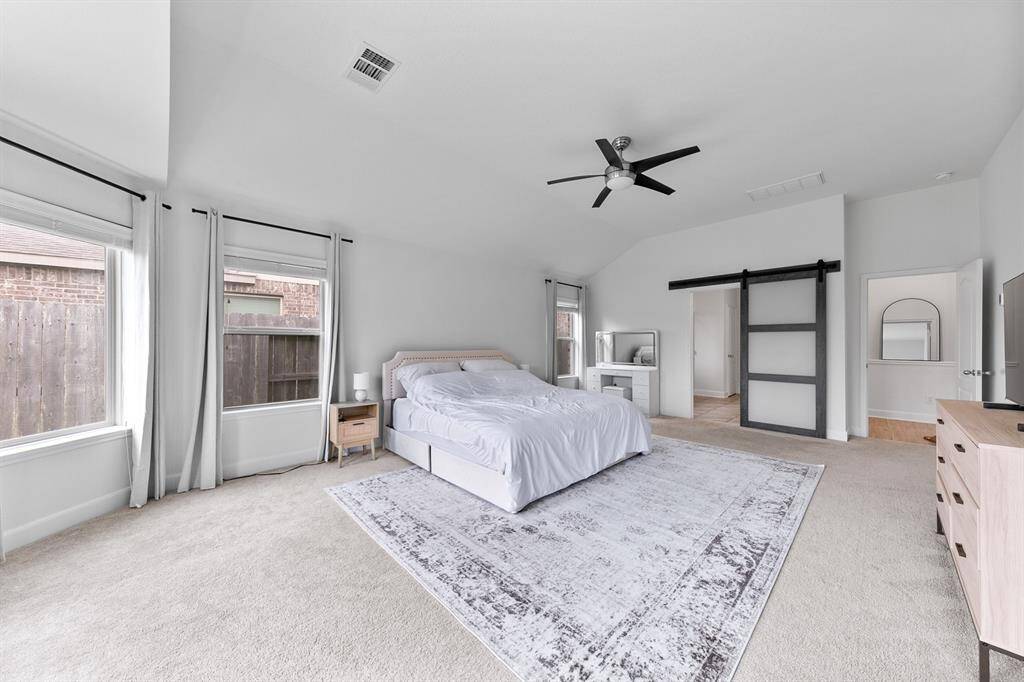A sleek paneled barn door separates the primary bedroom from the bath.