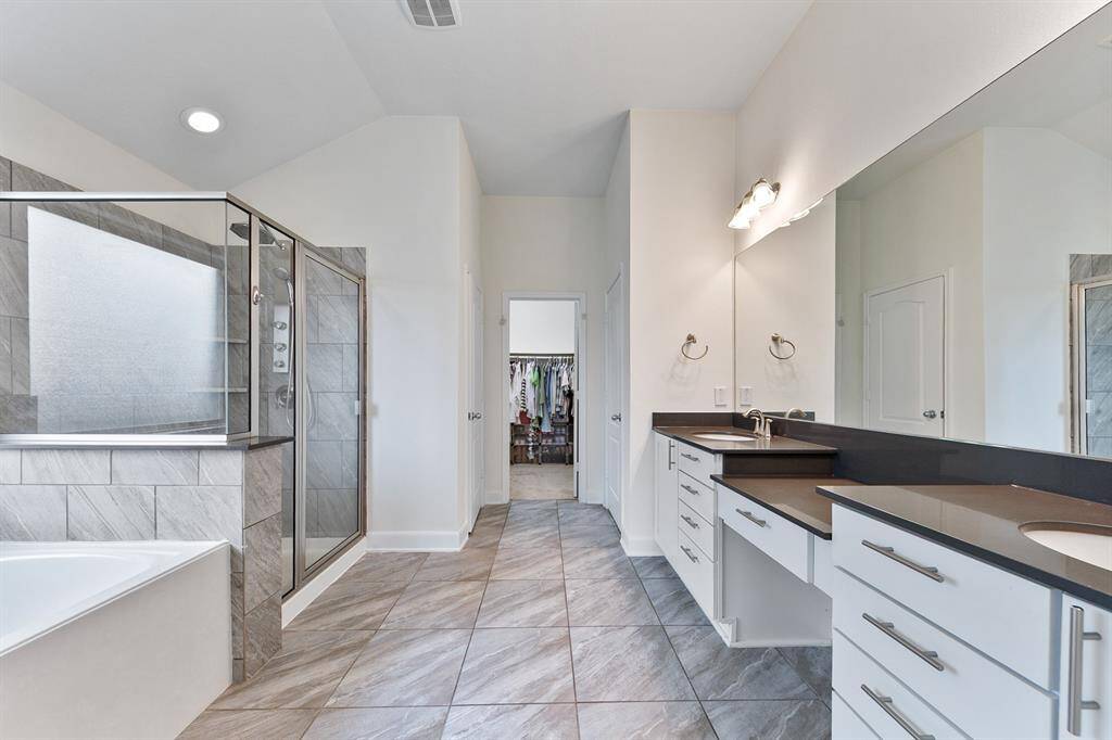 Spacious enough for 2, you'll love this primary bath. A vanity area separates two sinks that rest across from a soaking tub and separate shower.