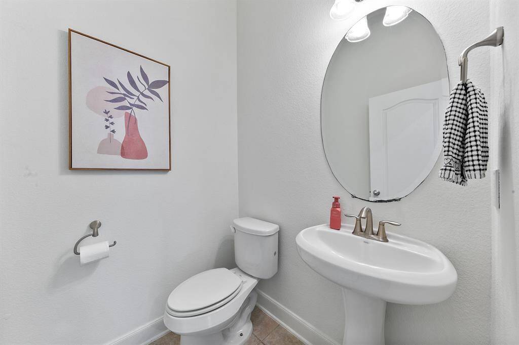 A convenient half bath offers a pedestal sink and classic lighting.