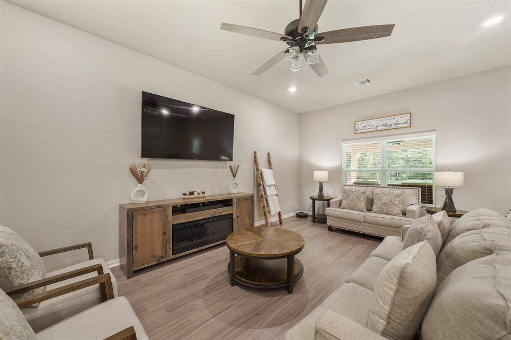 Stunning living room with vinyl floors, recessed lighting, a ceiling fan, and windows with privacy blinds.