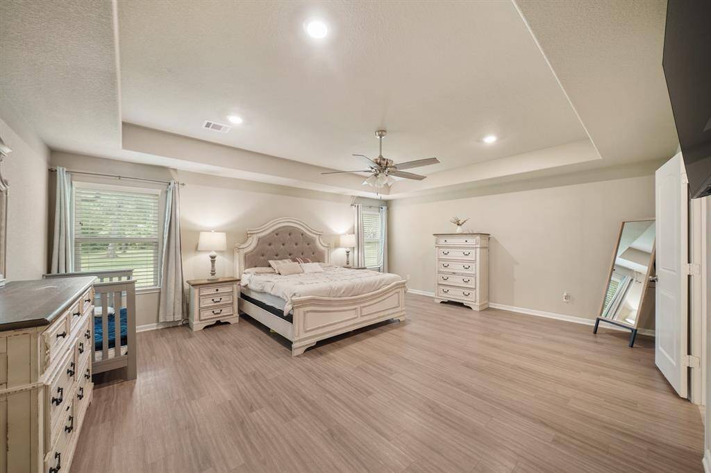 Unwind in this primary bedroom with vinyl floors, large windows with privacy blinds, a gorgeous tray ceiling with fan, and recessed lighting.
