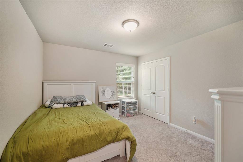 Secondary bedroom with carpet floors, window with privacy blinds, neutral paint, and a closet.