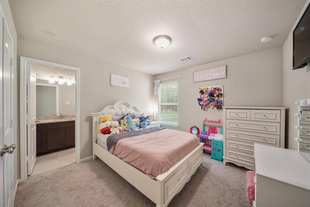 Spacious secondary bedroom with carpet floors, windows with blinds, and an en-suite bath.