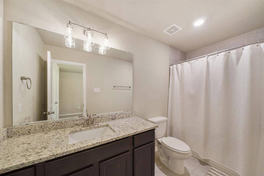 Secondary bathroom with granite countertops and backsplash, tile floors, and recessed lighting.