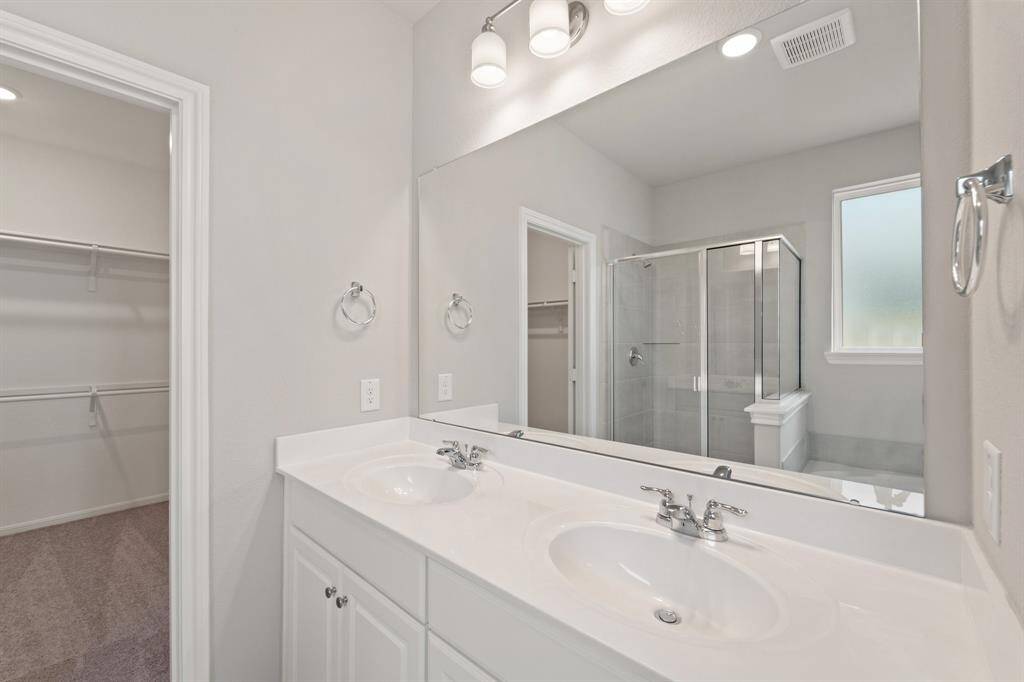 The en-suite bathroom offers a spa-like atmosphere with its elegant design, high end finishes, and tasteful lighting, creating a retreat within your own home.