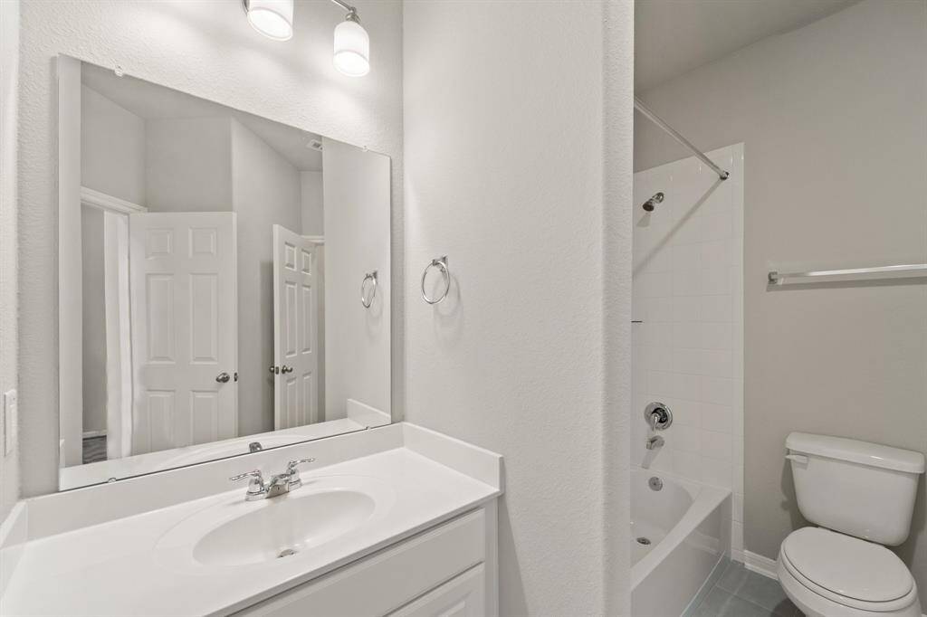 The secondary bath features tile flooring, white cabinetry and light countertops and a shower/tub combo. Perfect for accommodating any visiting family and friends.