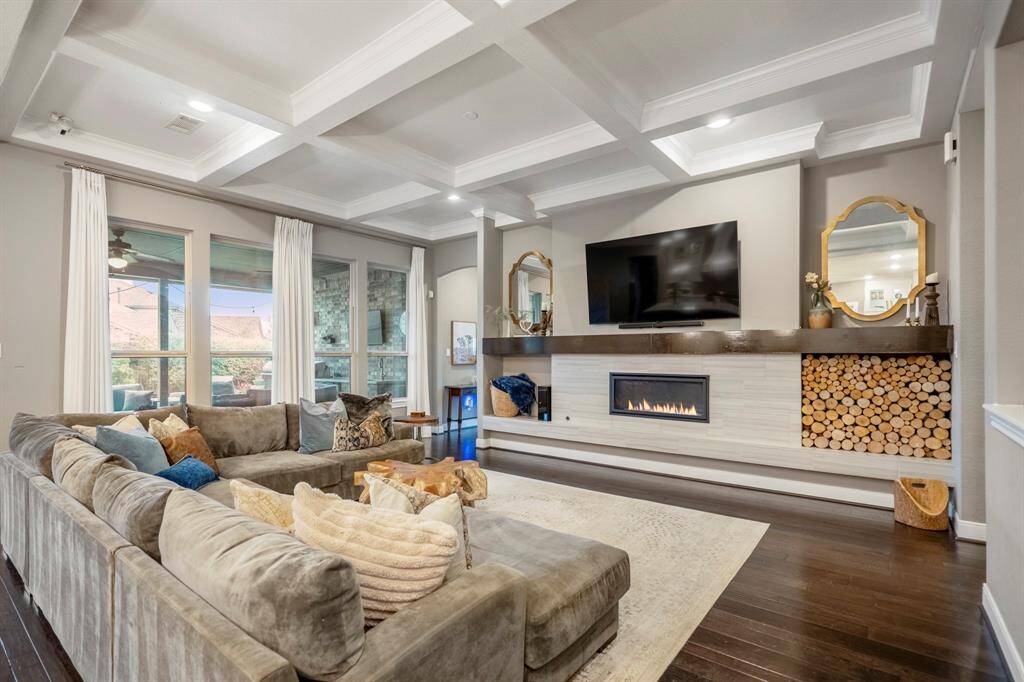 Gather the family and guests together in your huge living room! This stunning living room boasts a stunning modern gas fireplace and wood mantle, beamed ceilings, recesssed lighting, and large windows.