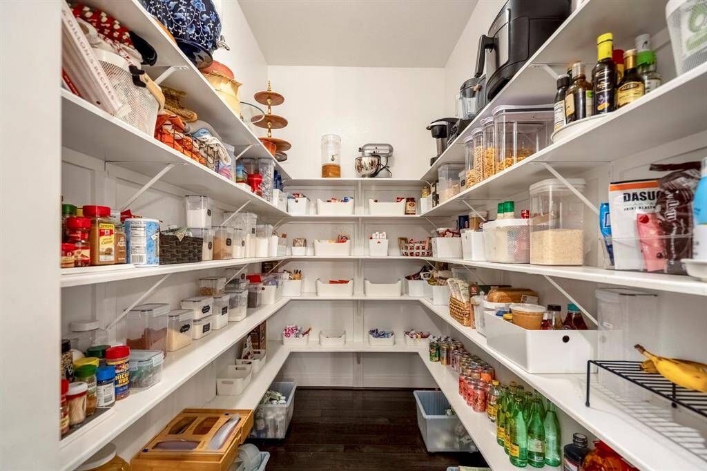 Tucked just off the kitchen, this spacious walk-in pantry offers abundant storage with custom shelving designed to keep everything organized and within reach.