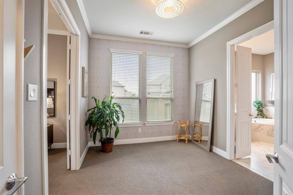 Connecting the primary bedroom and bathroom, is this spacious sitting room! It's complete with beautiful lighting, crown molding, accent wall, and plush carpet. It's perfect for a home gym, reading nook, or dressing room!