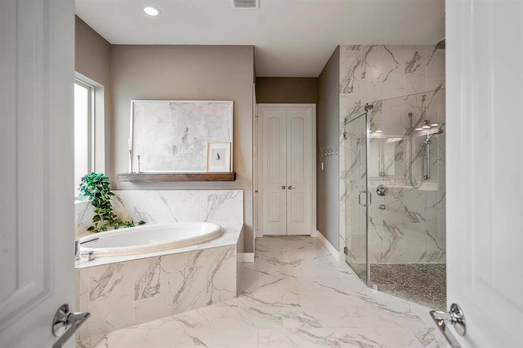 Step into comfort and style in this beautiful primary bathroom! Featuring a spacious walk-in shower with mud-set tile floors & frameless glass surround, a serene garden tub, and floating wood shelf for a modern touch. Natural light completes the warm and inviting feel!