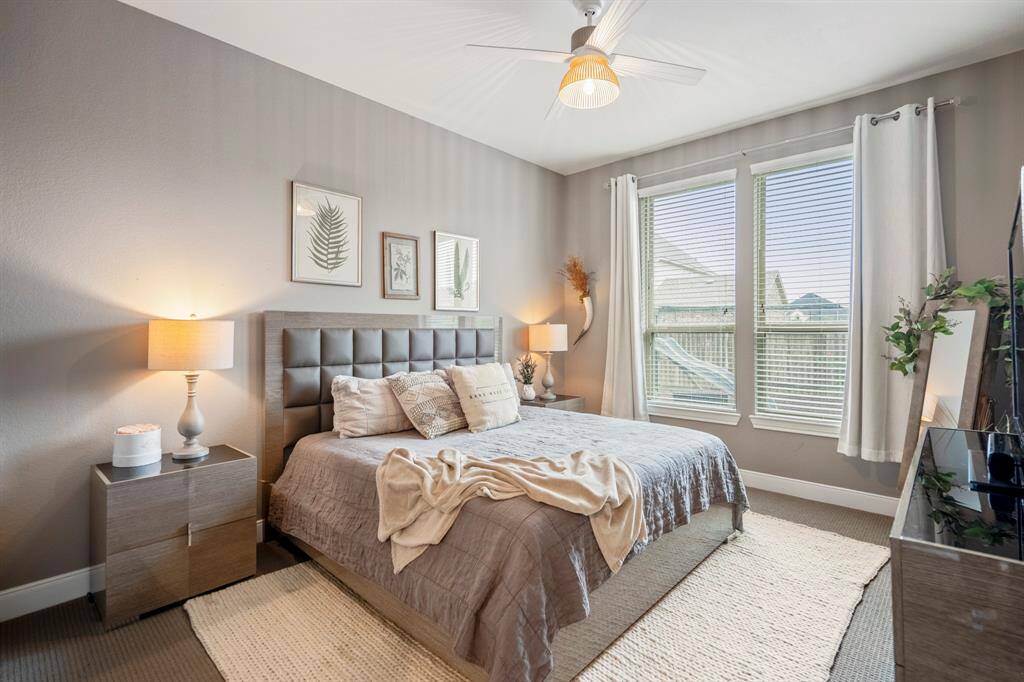 Nestled down its own private hallway, this downstairs secondary bedroom is complete with a ceiling fan, bright natural light, plush carpet, and private bathroom.
