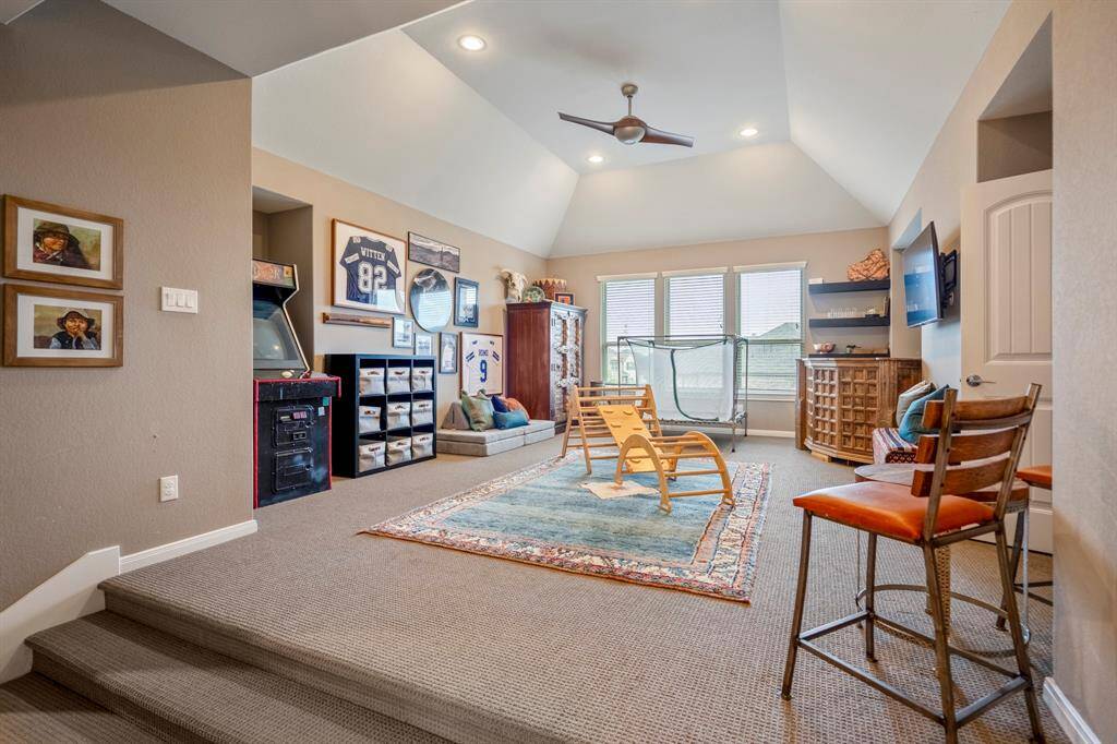 Upstairs you walk into a large game room that's perfect for a pool table, play area, or a lounging space! It features high ceilings, bright natural light, a ceiling fan, and plush carpet.