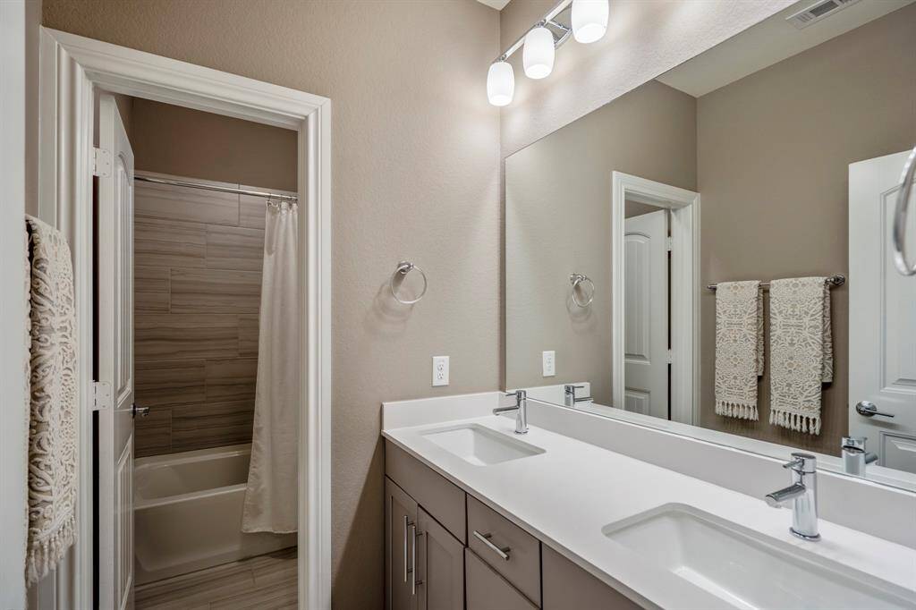 This full bathroom is located off the hall of the first secondary bedroom making it easy to share and get ready. It features a large vanity, dual sinks, quartz countertops, and offers additional privacy with separated vanity and shower making it easy to share and get ready.