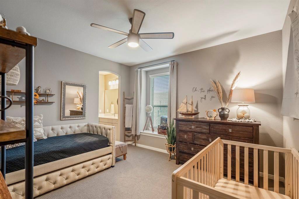 This secondary bedroom is complete with plush carpet, ceiling fan, and neutral paint, and it offers both comfort and convenience, featuring a private vanity area with direct access to a shared Jack-and-Jill bathroom—perfect for maintaining personal space while enjoying a connected layout.
