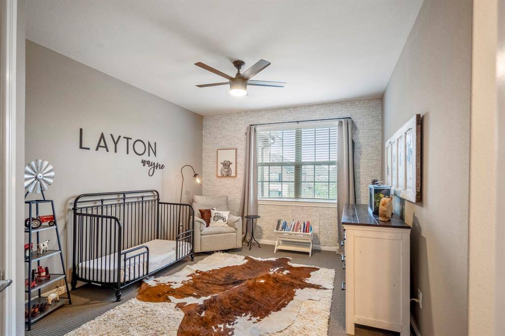 The final secondary bedroom features a custom accent wall, plush carpet, and ceiling fan, and it offers both comfort and convenience, featuring a private vanity area with direct access to a shared Jack-and-Jill bathroom—perfect for maintaining personal space while enjoying a connected layout.