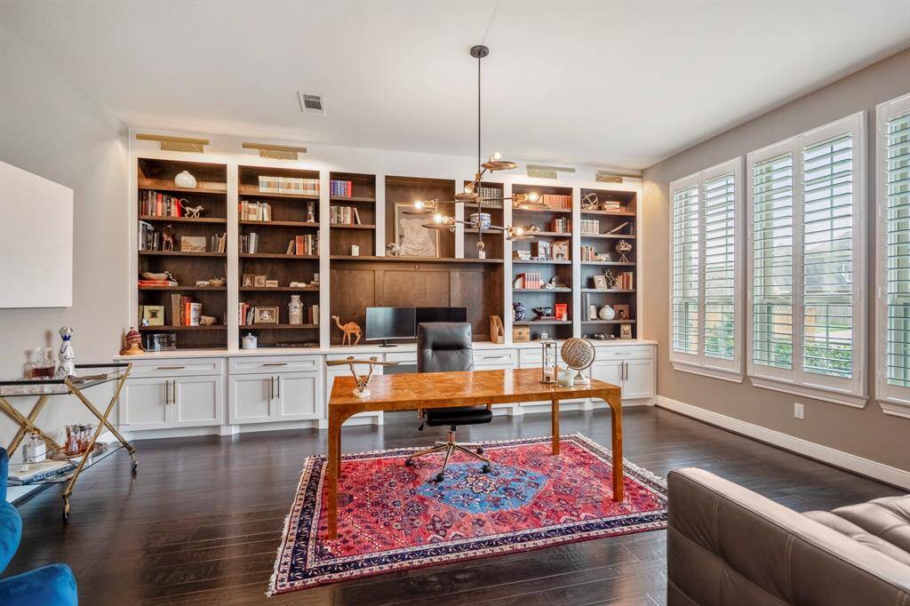 Enjoy working from home in this office space that's quietly tucked away at the front of the home! Featuring beautiful custom built-ins, modern chandlier and accent lighting, wood floors, and shutters - letting in plenty of natural light.