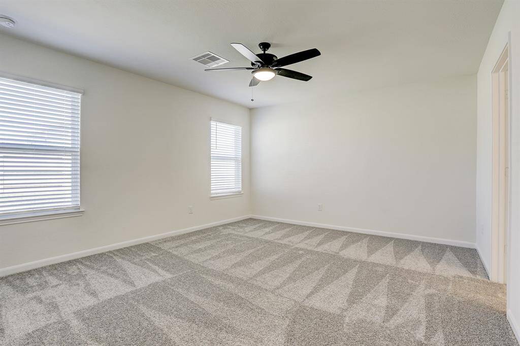 Spacious master bedroom with carpet floors and large walk in closet.