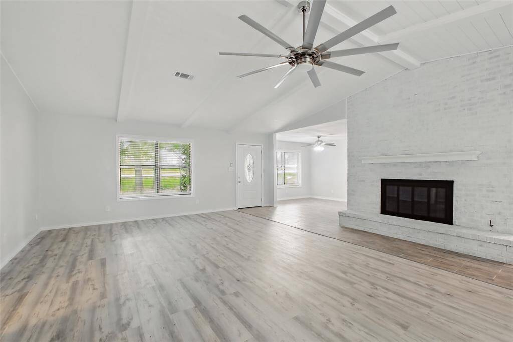Vaulted ceilings and a white brick fireplace set the tone for this bright, inviting living room—perfect for both cozy nights in and casual entertaining.